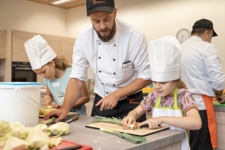 Koch Jürgen zeigt Kindern wie man Gemüse schnedet